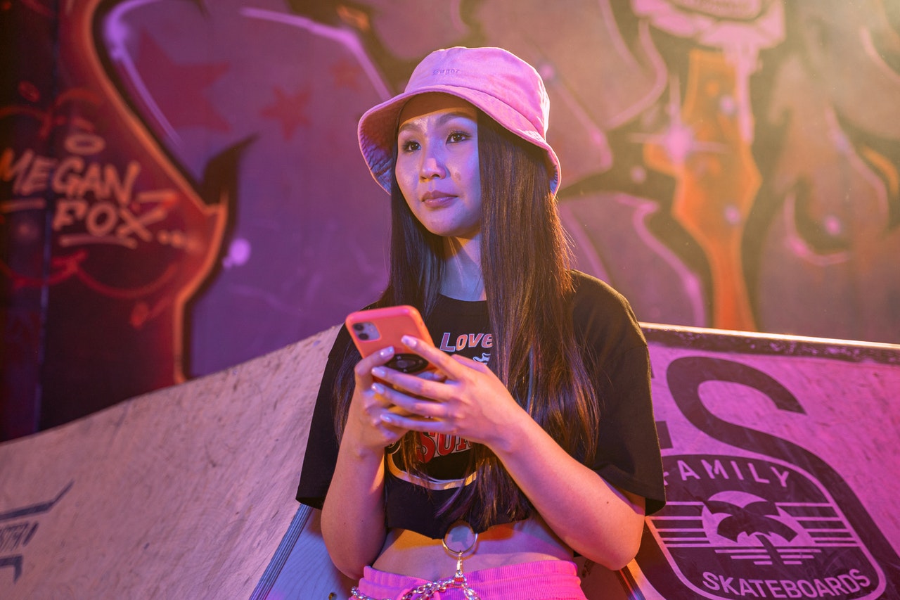 Young Woman in a Bucket Hat and Crop Top Using a Cellphone